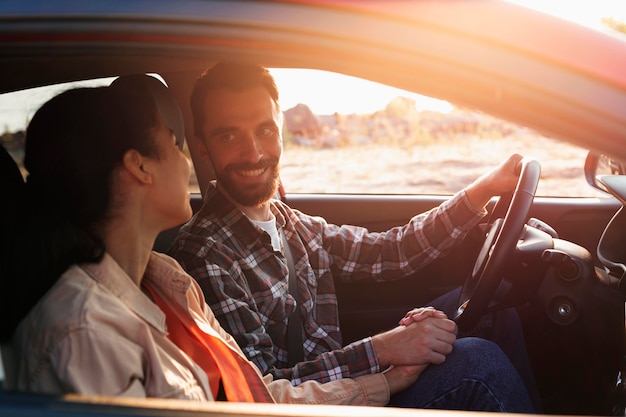 Photo gratuite couple souriant sur le côté voyageant en voiture