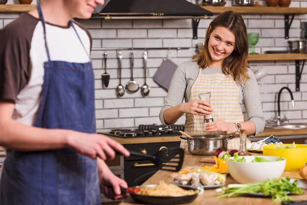 Couple souriant cuisine des plats ensemble