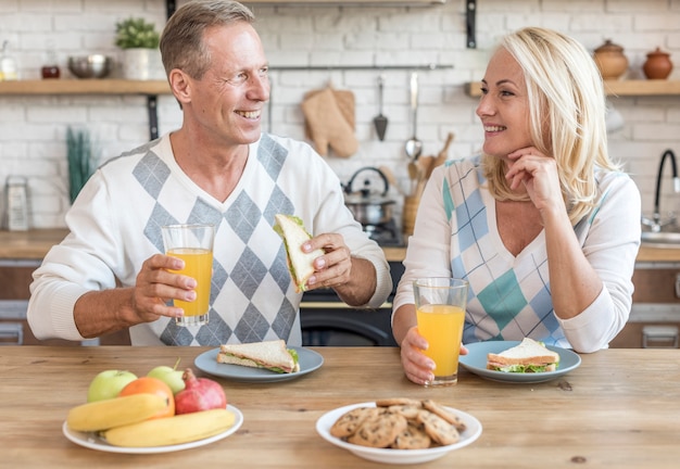 Couple souriant dans la cuisine prenant son petit déjeuner