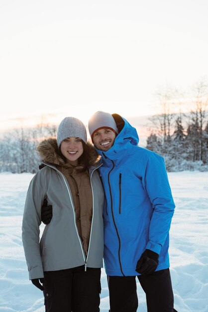 Couple souriant debout sur un paysage enneigé