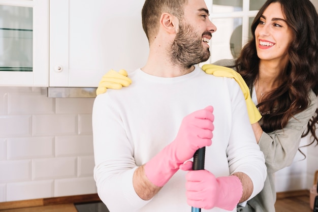 Couple souriant embrassant et nettoyant