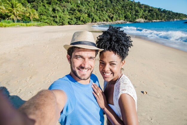 Couple souriant faisant selfie à la plage