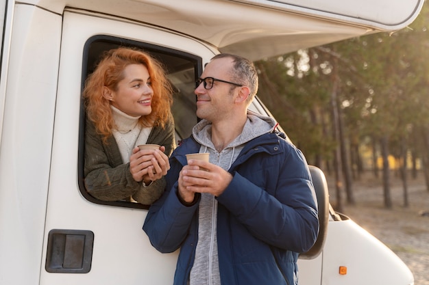 Couple souriant de plan moyen avec camping-car