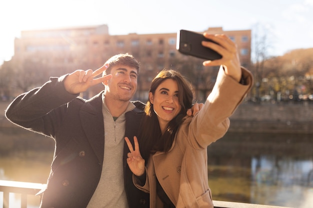 Couple souriant à plan moyen prenant un selfie