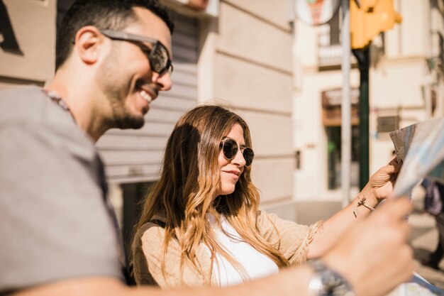 Couple souriant à la recherche de carte dans la ville