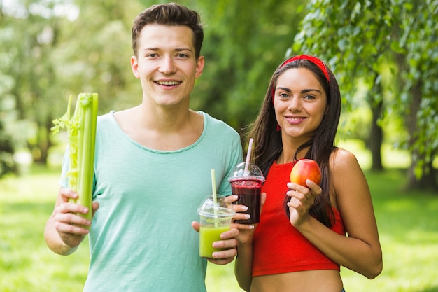 Couple souriant, tenue, avocat, et, pomme, smoothies, dans main