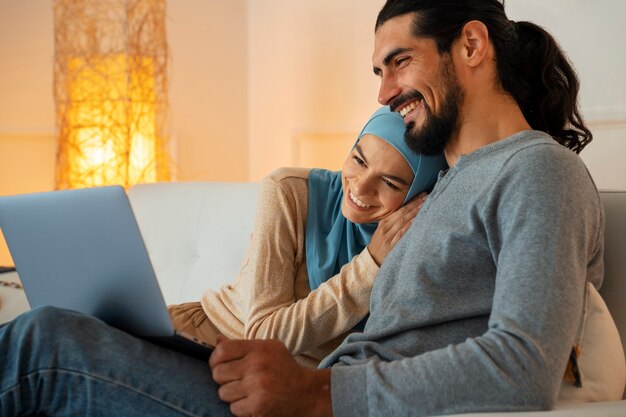 Couple souriant vue de côté avec ordinateur portable