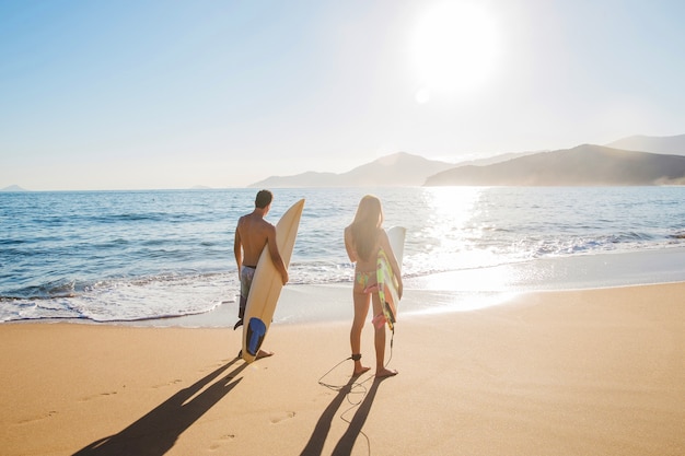 Couple de surfeurs sur la plage ensoleillée