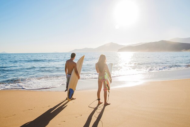 Couple de surfeurs sur la plage ensoleillée