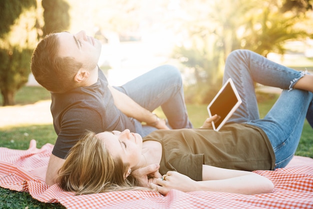 Couple avec tablette au repos dans le parc