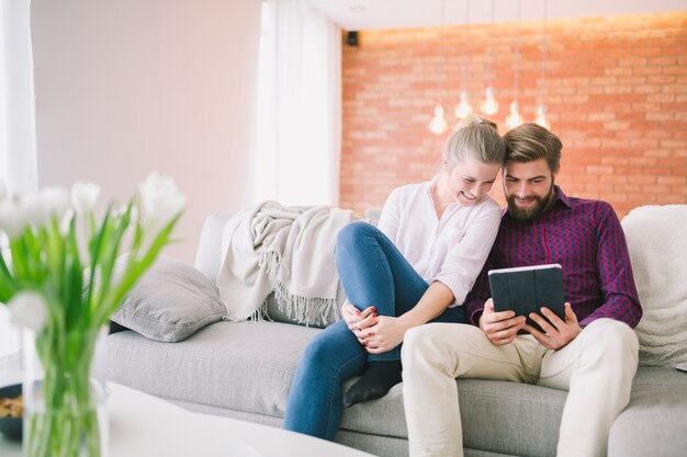 Couple avec tablette sur le canapé