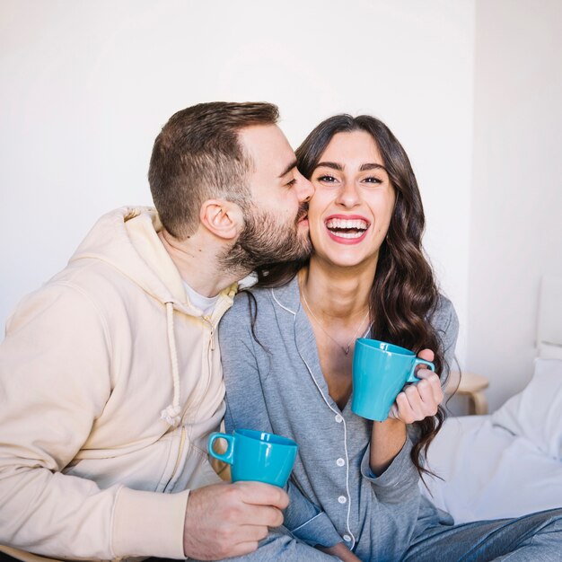 Couple avec des tasses en train de s&#39;embrasser