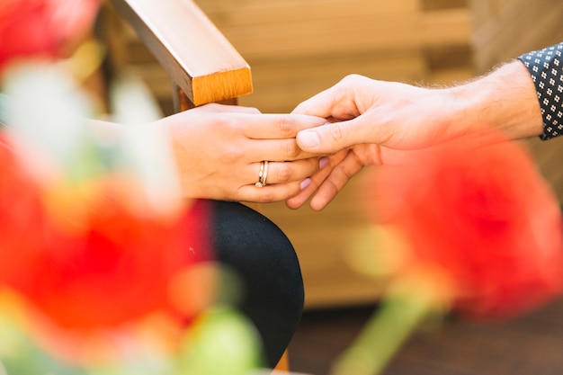 Photo gratuite couple tenant les mains devant une rose floue