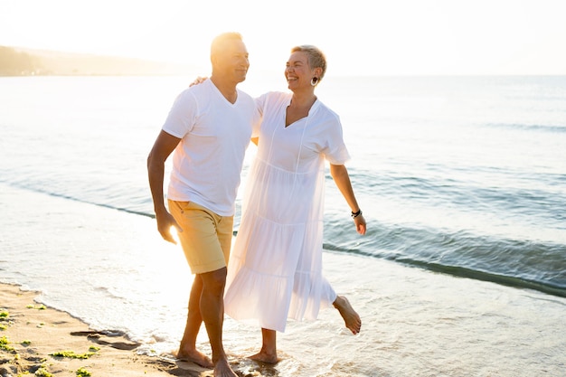 Couple de tir complet s'amusant au bord de la mer