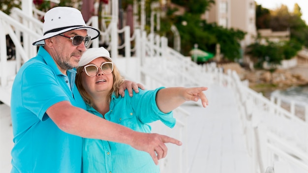 Couple de touristes aînés sur la plage en montrant quelque chose