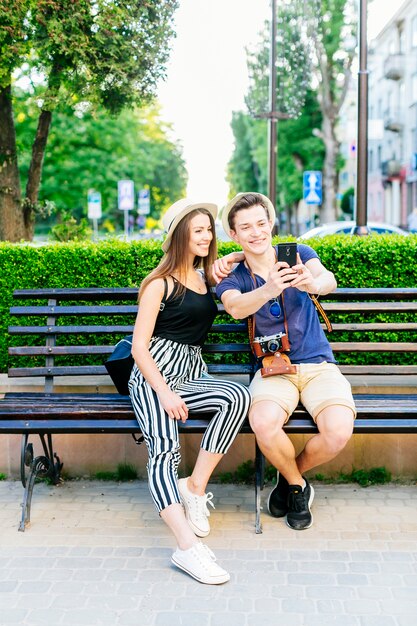 Couple de touristes sur un banc prenant un selfie