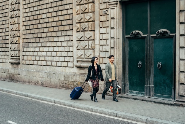 Couple de touristes heureux asiatiques marchant avec valise