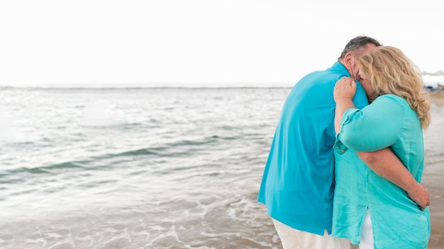Couple de touristes senior embrassé sur la plage