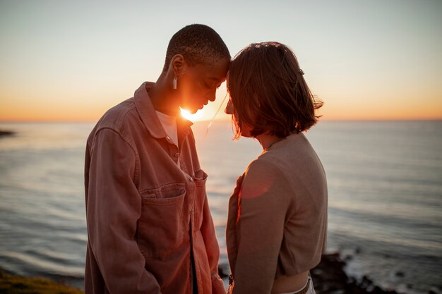 Couple trans main dans la main au coucher du soleil sur la plage