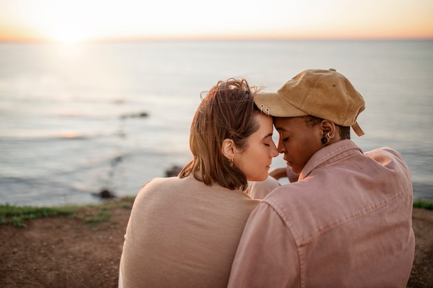 Photo gratuite couple trans se tenant sur la plage au coucher du soleil