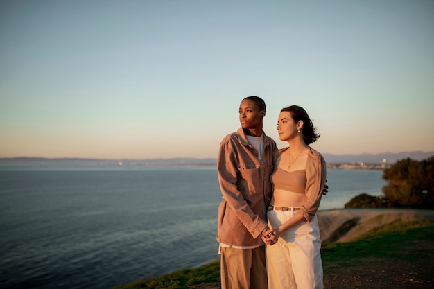 Couple trans se tenant sur la plage en regardant le coucher du soleil