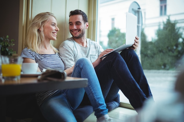 Couple en utilisant la tablette numérique dans cafÃ ©