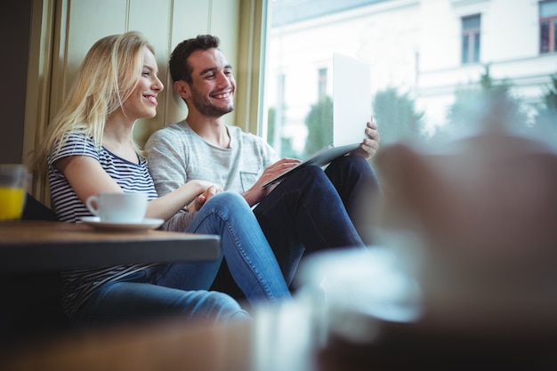 Couple en utilisant la tablette numérique dans cafÃ ©