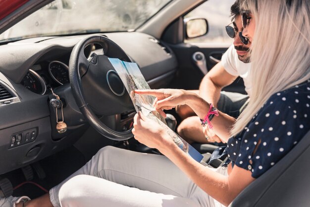 Couple en vacances assis dans la voiture en regardant la carte