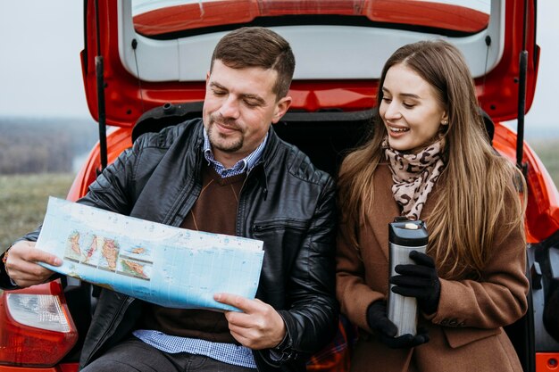 Couple vérifiant une carte dans le coffre de la voiture