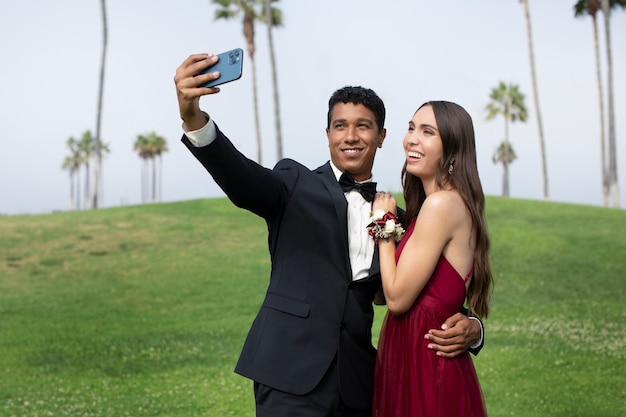 Couple en vêtements de bal de fin d'études prenant un selfie