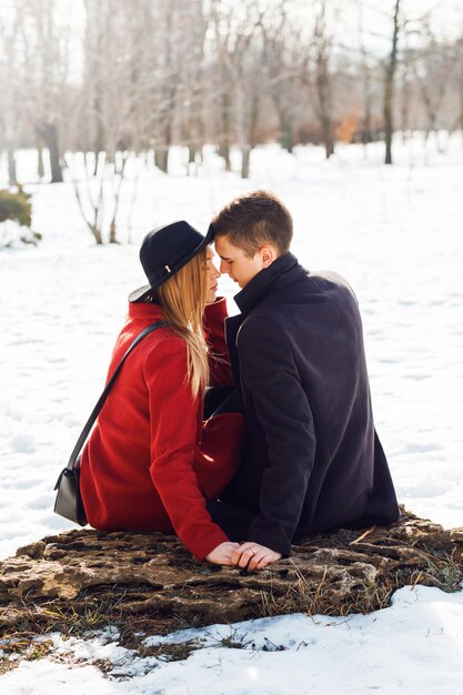 Couple en vêtements d'hiver s'embrasser un jour de neige