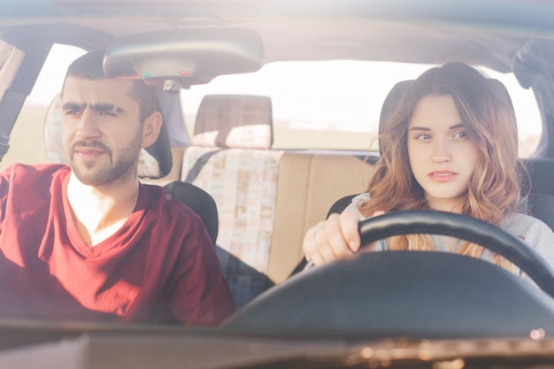 Couple en voiture en voyage: une conductrice expérimentée concentrée est assise au volant et son mari