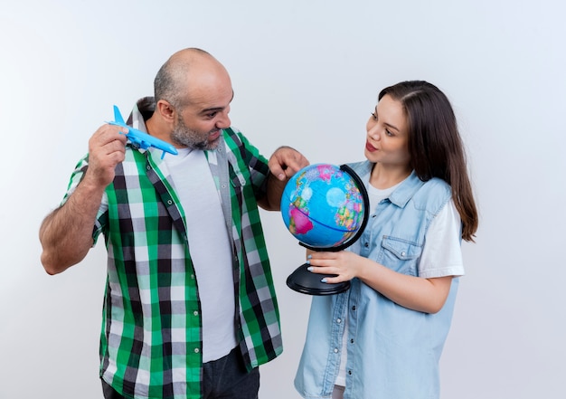Couple de voyageurs adultes impressionné homme tenant un avion modèle regardant et touchant le globe et heureux woman holding globe et le regardant