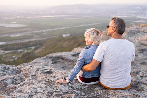 Couple de voyageurs plein coup assis sur la falaise