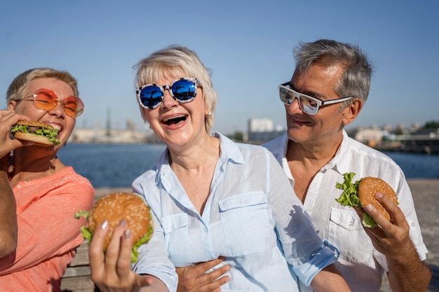 Couples âgés à la plage en dégustant des hamburgers