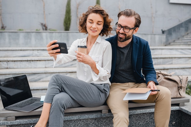 Couples attrayants d'homme et de femme s'asseyant sur des escaliers dans le centre-ville urbain