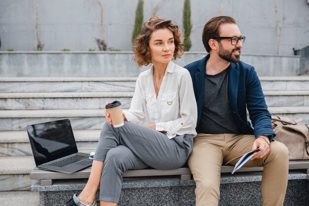 Couples attrayants d'homme et de femme s'asseyant sur des escaliers dans le centre-ville urbain