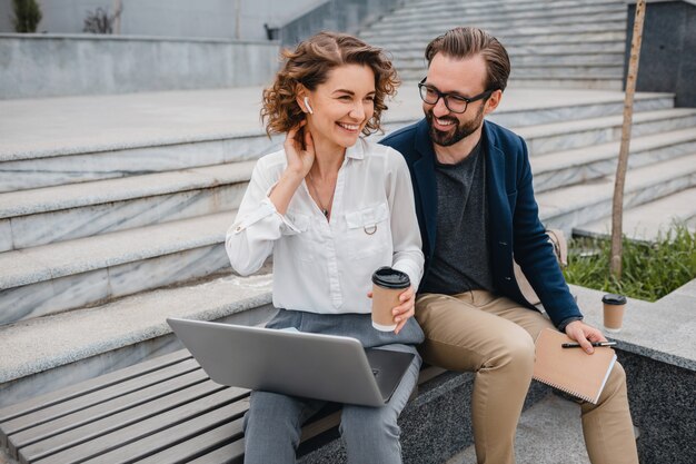 Couples attrayants d'homme et de femme s'asseyant sur des escaliers dans le centre-ville urbain