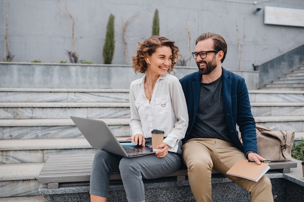 Couples attrayants d'homme et de femme s'asseyant sur des escaliers dans le centre-ville urbain