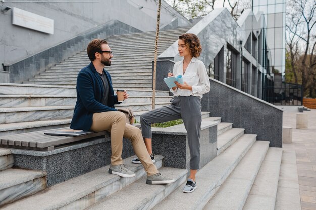 Couples attrayants d'homme et de femme s'asseyant sur des escaliers dans le centre-ville urbain