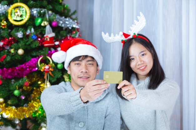 couples en chapeau de noël tenant une carte de crédit
