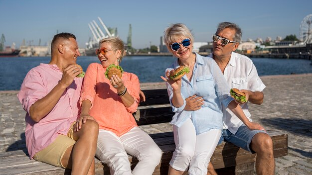 Couples plus âgés à la plage de manger des hamburgers