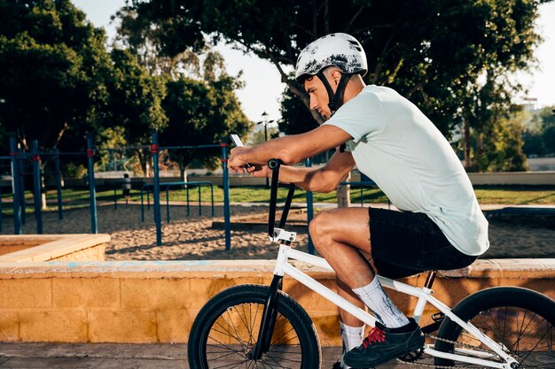 Coureur de BMX regardant le téléphone long shot