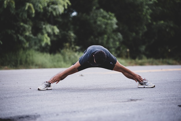 Coureur masculin faisant des exercices d'étirement, se préparant à l'entraînement