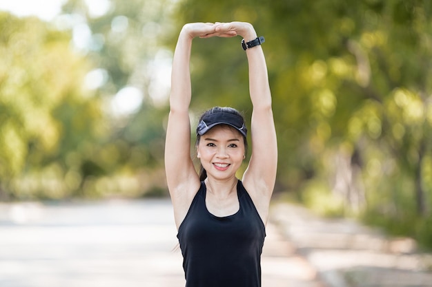 Une coureuse asiatique joyeuse en tenue de sport faisant des étirements