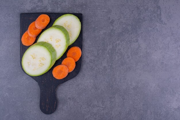 Courgettes et carottes coupées en tranches sur un plateau noir