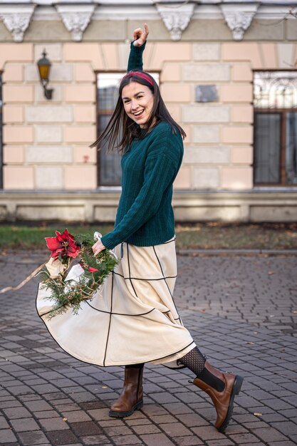 Couronne de Noël entre les mains d'une femme élégante, promenade en ville, attendant Noël.