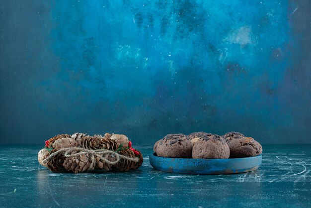 Couronne de Noël et une portion de biscuits sur bleu.