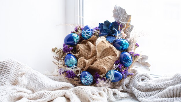 Couronne de Pâques avec des oeufs bleus avec des paillettes à la fenêtre.