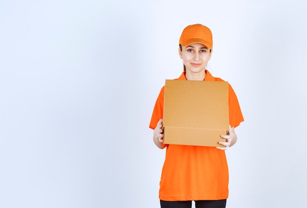 Courrier femelle en uniforme orange tenant une boîte en carton ouverte.